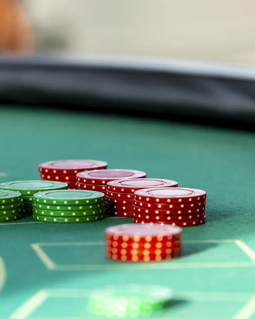 Zöld posztós blackjack-asztal részlete párnázott kartámasszal és zsetonoszlopokkal