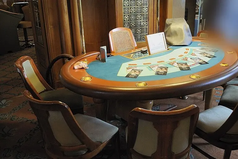 Kék posztós blackjack-asztal kárpitozott székekkel egy kaszinó játéktermében