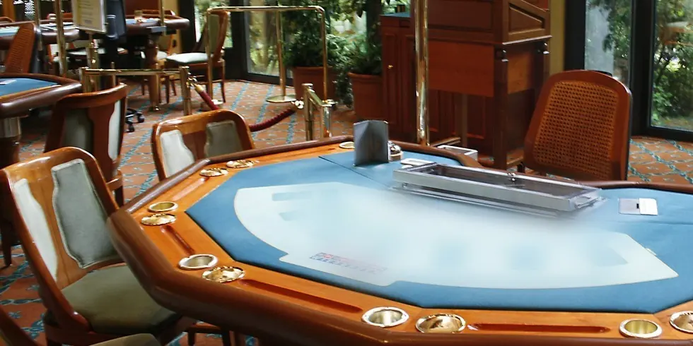 Kék posztós blackjack-asztal lakkozott fa kávával és kárpitozott székekkel egy kaszinóteremben